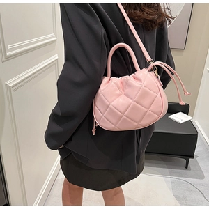 Pink quilted leather crossbody bucket bag shown on model wearing black suit jacket