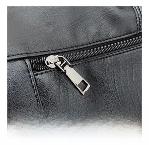 Detail view of the smooth metallic zipper and fine stitching on a black leather tote bag