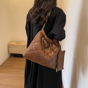 Brown quilted tote bag with chain strap and small matching coin purse on a model