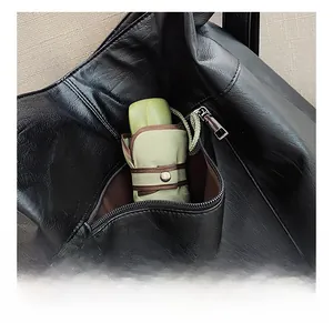 Detail of the back zipper pocket on a black leather tote showing umbrella storage