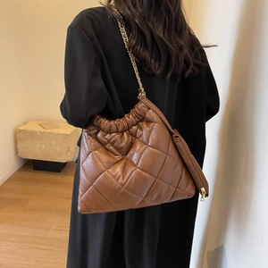 Detail of dark brown quilted tote bag with gold chain strap and mini side pouch