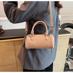 Detail of pleated apricot cylinder bag showing soft PU texture and shoulder strap