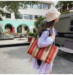 Detailed close-up of colorful striped canvas tote bag with leather straps for daily use
