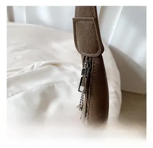 Macro detail of silver-tone metal zipper and chain on deep brown leather tote bag