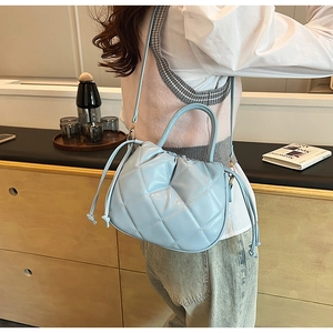 Close-up of a light blue quilted crossbody bucket bag with drawstring closure detail