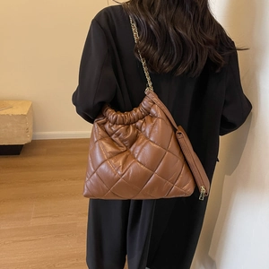 Detailed view of brown quilted leather tote with elegant gold chain strap and mini pouch