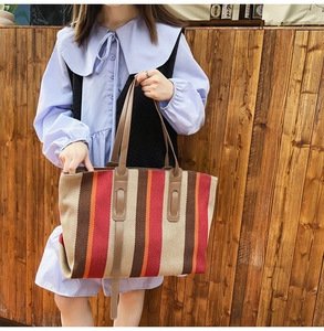 Detail of the colorful striped canvas tote bag featuring premium leather handles