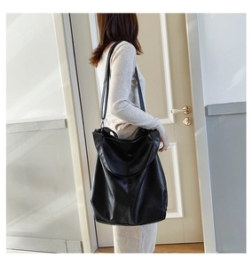 Minimalist black faux leather tote bag with wide shoulder strap for daily commuting