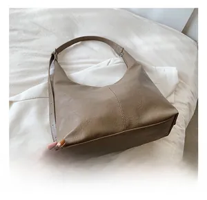 Close-up of khaki tote bag showing vintage wrinkled PU leather texture and reinforced stitching