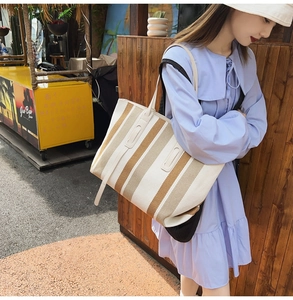 Outdoor shot of striped canvas tote bag with cream handles on a model in blue dress