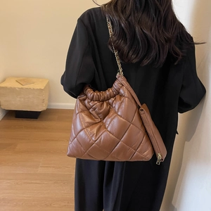 Detail of brown quilted tote bag with gold chain strap and matching small zipper pouch