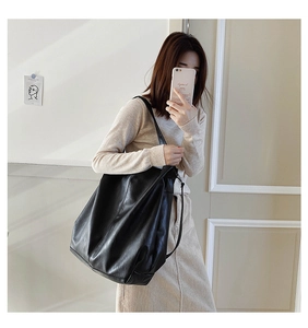 Detail of a large black PU leather tote bag with soft texture and natural drape design