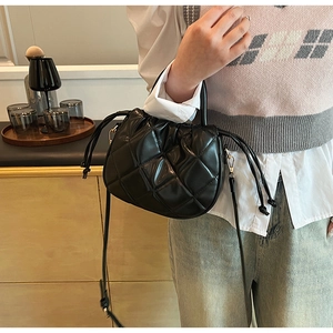 Detail of black quilted PU leather crossbody bag with drawstring and gold hardware