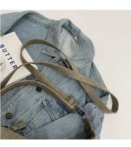 Detail of adjustable olive green shoulder bag strap with gunmetal swivel hooks on denim