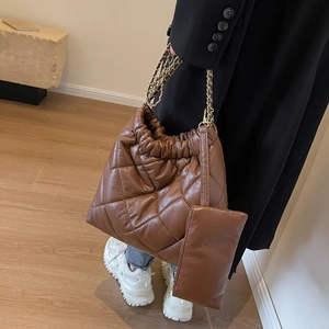 Detail of brown quilted tote bag with chain strap and matching small zipper pouch