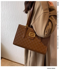 Detailed view of brown checkered tote bag featuring gold buckle and thin shoulder straps