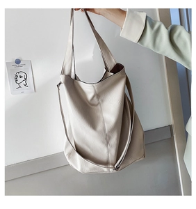 Detail of a minimalist cream white large tote bag with top handle and thin shoulder strap