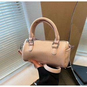 Detail of pink cylindrical handbag with vertical embossing and silver hardware