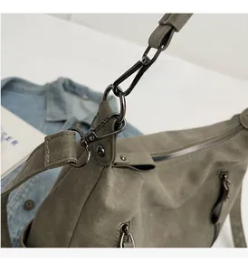 Detail of high-quality gunmetal hardware and matte grey-green leather on a large tote bag