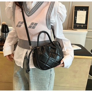 Detail of black quilted crossbody bag with drawstring closure and golden hardware