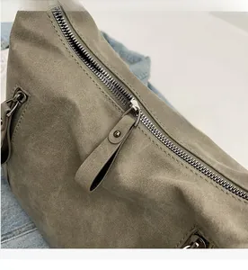 Detail of smooth silver zipper and textured grey-green fabric on the large tote bag