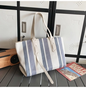 Detail shot of a large striped canvas tote bag against a minimalist indoor background