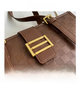Close-up of brown checkerboard leather bag with gold square buckle and neat stitching