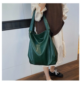 Detail of dark green oversized faux leather hobo tote bag shown on a female model