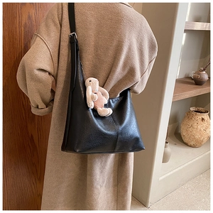 Detail of black large tote bag with lychee texture and pink plush rabbit charm