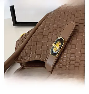 Détail de la texture en cuir tressé marron et du fermoir doré de ce sac à main élégant