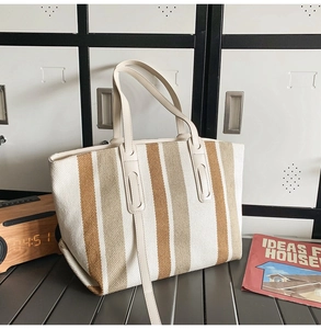 Detail of striped canvas tote bag with woven texture and premium leather handles