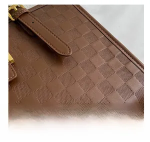 Detailed close-up of brown checkered embossed leather bag with gold buckle hardware