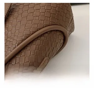 Détail de la texture cuir tressé marron et des ferrures dorées sur le sac seau chic