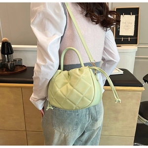 Pistachio green quilted bucket bag with drawstring closure and crossbody strap