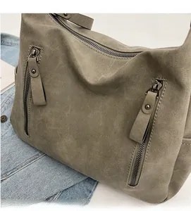 Detailed macro view of soft gray-green suede fabric and vertical zipper pockets on tote bag