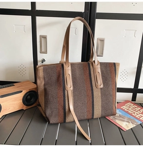 Vertical striped canvas tote bag with leather straps on a metallic table background