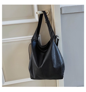 Detail view of large black tote bag in soft leather texture hanging on a door handle