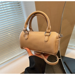 Detailed view of beige barrel bag featuring vertical pleated texture and dual handles
