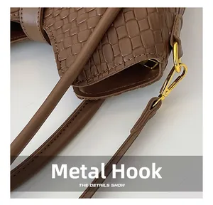 Gros plan du crochet doré et de la texture en cuir tressé d'un sac seau marron