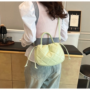 Detail of mint green quilted crossbody bag with stylish side drawstring and round handle