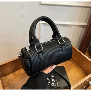 Detail of black quilted bowling bag with vertical stripes and silver metal zipper