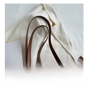 Detail of brown checkered tote bag with golden metal hardware and sturdy handle