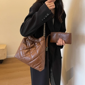 Deep brown quilted leather tote bag set with gold chain straps on a female model