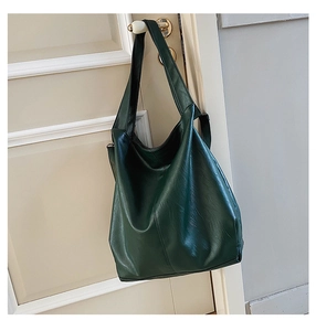 Close-up of a dark green soft PU leather hobo bag hanging on a beige handle