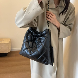 Close-up of black quilted leather tote bag with gold chain strap and drawstring detail