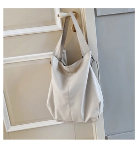 Detail of soft cream leather hobo tote bag hanging on a vintage door handle