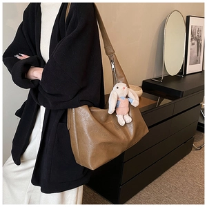 Detail of soft brown tote bag with smooth leather texture and a cute rabbit pendant