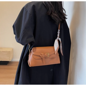 Detail of warm brown pebbled leather crossbody bag with vintage buckle and silk scarf