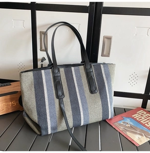 Detail of striped canvas tote bag with black round handles and a crossbody strap