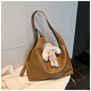 Close-up of vintage brown tote bag with natural texture and cute white plush rabbit charm